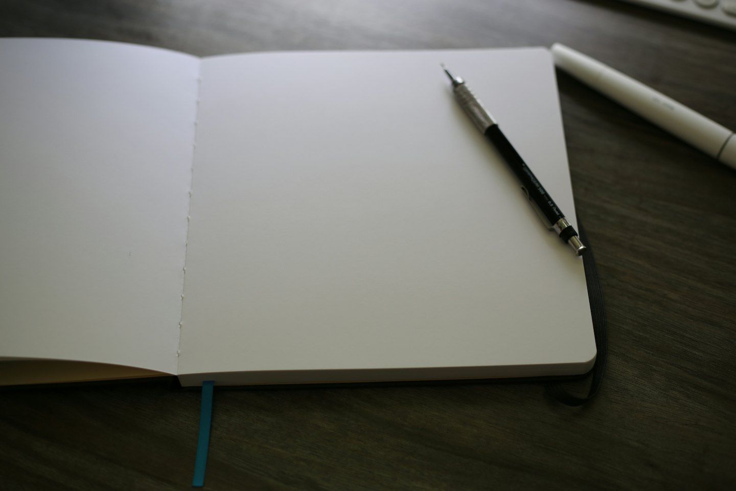 Un cuaderno en blanco con un lápiz sobre un escritorio de madera.