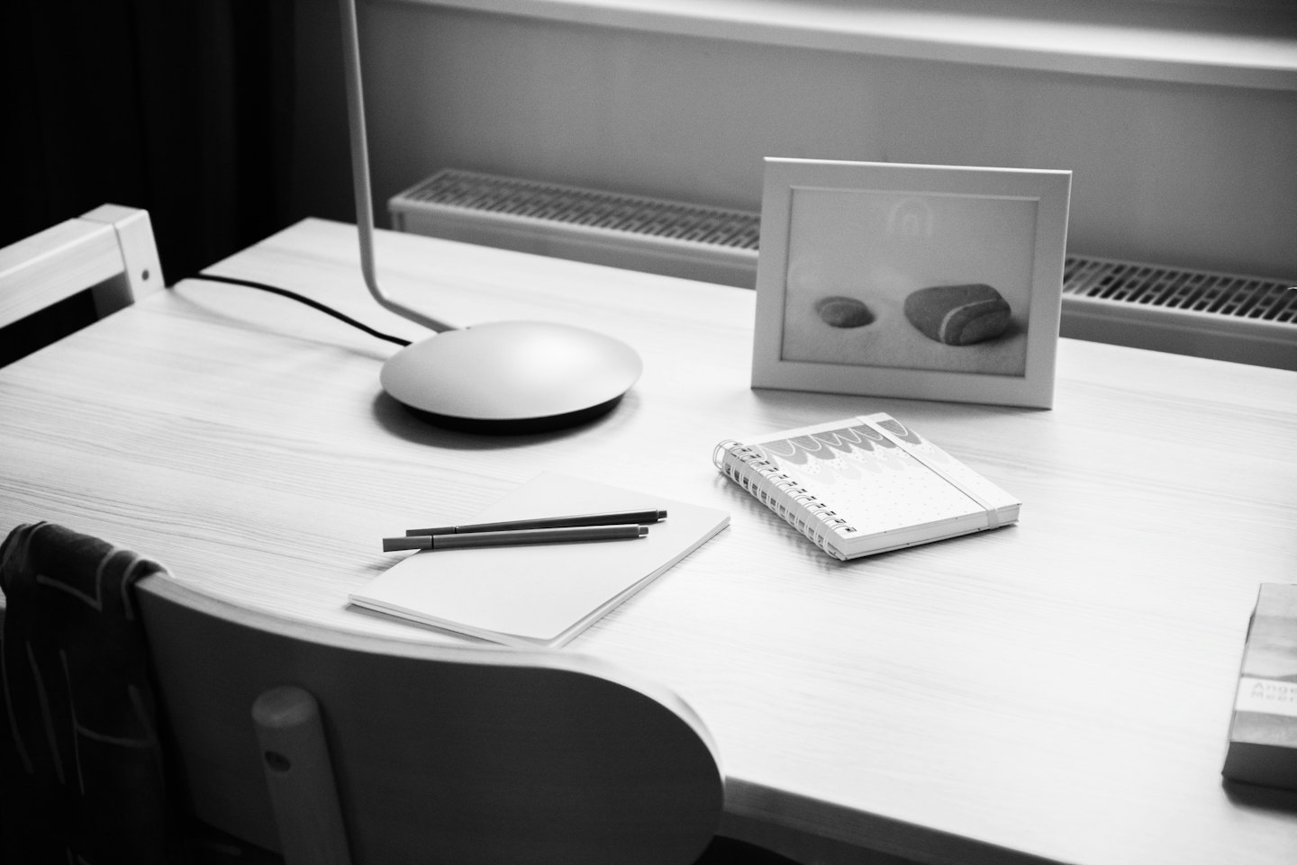 Escritorio de madera minimalista con lámpara, cuaderno y material de papelería.
